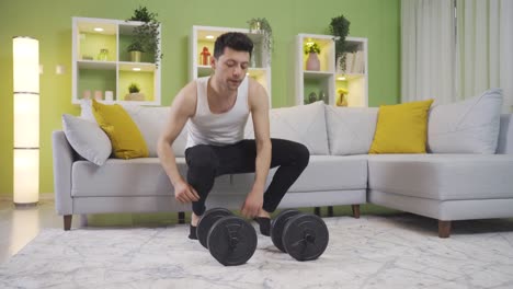 Funny-and-clumsy-young-man-drops-a-dumbbell-on-his-foot-while-working-out-at-home.